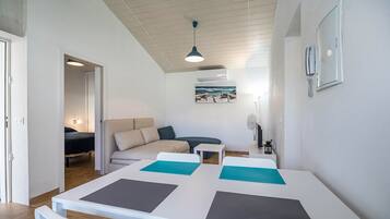 A modern room with a dining table, a sofa, a small table, and a ceiling fan.