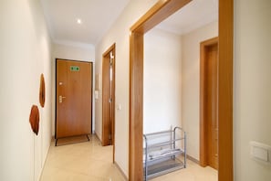 A hallway with wooden doors, a metal rack, and a sign indicating a bathroom. - Apartment 'Yara Beach Apartments T1' with Shared Pool, Wi-Fi and Air Conditioning (Albufeira)