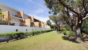 A modern building with a flat roof, a well-maintained lawn, and a large tree. - Apartment 'Yara Beach Apartments with Terrace' with Shared Pool, Wi-Fi and Air Conditioning (Albufeira)