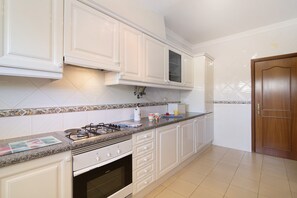 A kitchen with white cabinets, a gas stove, a microwave, and a wooden door.