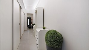 Un pasillo con paredes blancas, una planta en maceta y una puerta al final.