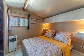 A bedroom with a bed, a window, a wall-mounted air conditioner, and a bedside lamp.