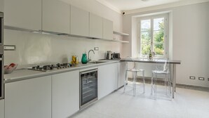 Een moderne keuken met witte kasten, een inbouwoven en een raam met uitzicht op groen.