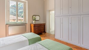 Een slaapkamer met twee bedden, een dressoir, een spiegel en een grote kledingkast.