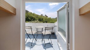 Un balcón con una mesa y sillas, vista al cielo y una puerta que da al interior.