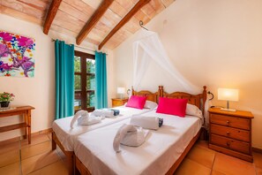 A double bed with white linens, a wooden headboard, and a canopy. There are two bedside tables with lamps and a small wooden dresser. - Country House 'Son Favar Capdepera' with Private Pool, Private Terrace and Wi-Fi (Capdepera)