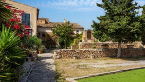 A stone pathway leading to a building with a tiled roof, surrounded by greenery and a stone wall. - Country House 'Son Favar Capdepera' with Private Pool, Private Terrace and Wi-Fi (Capdepera)
