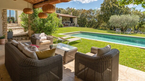 A patio with wicker furniture, a glass table, and a view of a swimming pool and house. - Villa 'Les Terrasses De Gordes' with Private Pool, Private Terrace and Wi-Fi (Gordes)