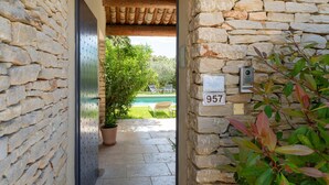 A stone-walled corridor leading to a pool area with a potted plant and a sign with the number 957. - Villa 'Les Terrasses De Gordes' with Private Pool, Private Terrace and Wi-Fi (Gordes)