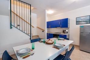 A compact kitchen with blue cabinets, a dining table set with plates, glasses, and a cake, and a staircase with a handrail.