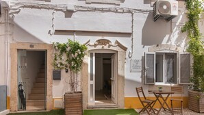 Un edificio con una escalera, una puerta, una ventana y una mesa con sillas.