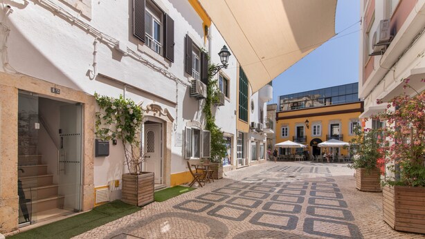 Un patio con piso de baldosas, mobiliario exterior y una escalera que lleva a la entrada.