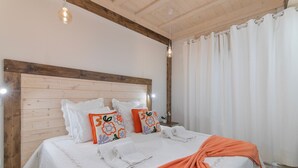 Una cama con ropa de cama blanca, cabecera de madera y almohadas decorativas.