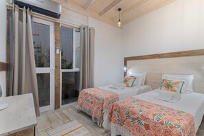 Een hotelkamer met twee bedden, een houten plafond, een schuifglazen deur en een klein tafeltje.
