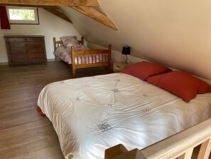 A bedroom with a wooden bed, a nightstand, a dresser, and a window.