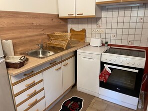 Cocina compacta con lavabo, lavavajillas, estufa y encimera de madera.