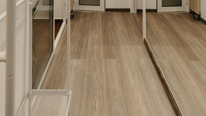 A hallway with wooden flooring, white walls, and frosted glass doors.