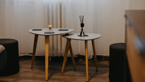 Two round tables with wooden legs and black placemats, a candle, and a black incense holder on one table.