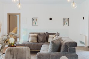 A modern living room with a grey sectional sofa, a glass coffee table, and a minimalist decor.