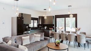 Een moderne woonkamer met een grijze bank, een ronde salontafel en een eethoek met grijze stoelen en een tafel.