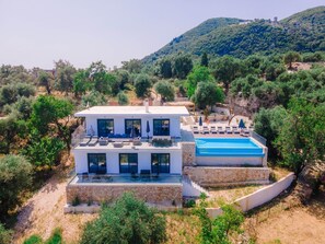 Une maison moderne à deux étages, dotée d’une piscine, d’un espace extérieur aménagé et offrant une vue sur le paysage environnant.