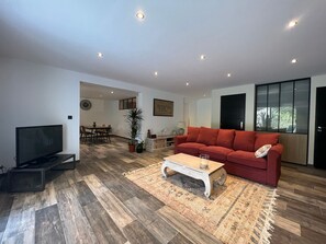 A modern living room with a red sofa, a coffee table, and a TV.