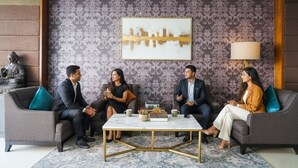 A meeting room with four people seated on a grey sofa, a coffee table, and a Buddha statue in the corner. - FabHotel VJR Electronic City (Bengaluru)