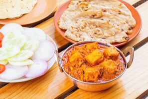 Plato con curry de paneer, pan naan y una ensalada.