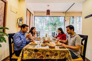 A dining area with a table set for four people, a fire extinguisher on the wall, and a sign indicating a restaurant. - Fabhotel Corporate Crown (Bengaluru)