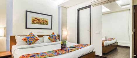 Quarto de hotel moderno com uma cama grande, um ventilador de teto, uma moldura com uma fotografia na parede e um espelho na porta.