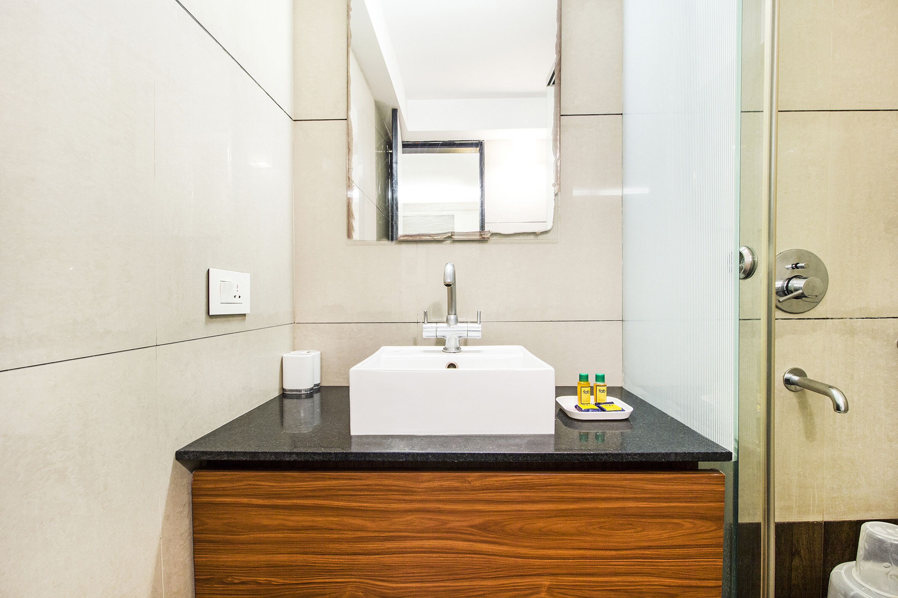 A modern bathroom with a white sink, wooden vanity, and a glass shower enclosure.
