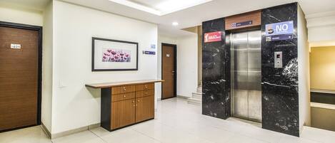 A modern elevator with a "NO SMOKING" sign, a reception desk, and a framed picture on the wall.
