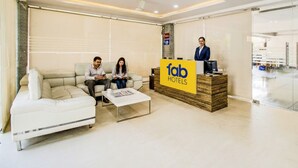 A hotel reception area with a reception desk, a sofa, and a coffee table. - Fabhotel Pearl City (Hyderabad)