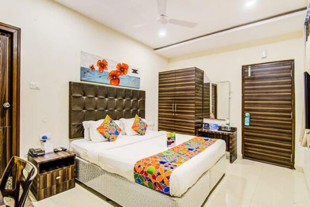 Une chambre à coucher comprenant un lit, une table de chevet, une commode, un ventilateur de plafond et un tableau accroché au mur.