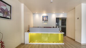 A reception desk with a glass front, a framed picture above it, and a small plant beside it. - Treebo Cabana (New Delhi)