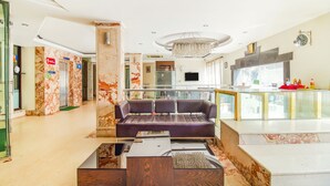 A modern lobby with a marble floor, a central seating area, a chandelier, and a glass partition with a counter. - FabHotel Marble Arch - Nr. Karol Bagh Market (New Delhi)