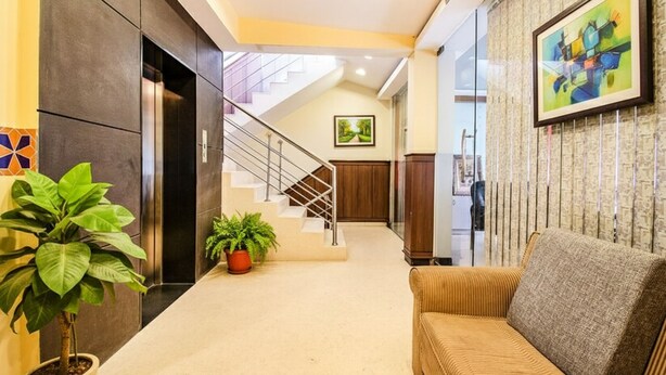 Un hall d’hôtel avec un escalier, un canapé et des plantes en pot.