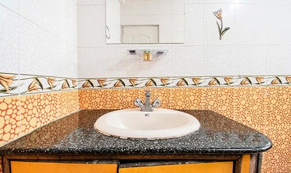 Casa de banho com lavatório, espelho e azulejos decorativos.