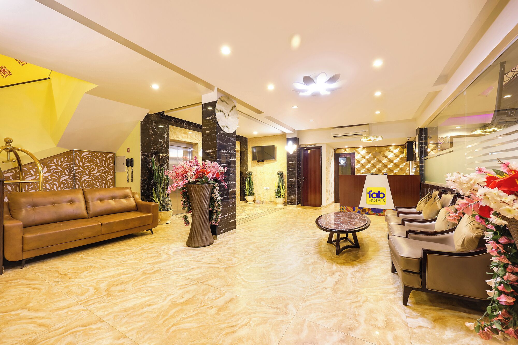 A hotel lobby with a leather sofa, a round table, and a reception desk.
