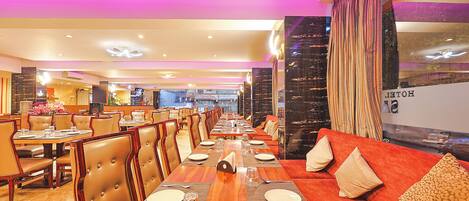 A restaurant with multiple dining tables, cushioned booths, and a view of the street outside.
