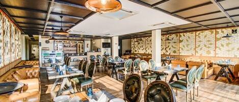 A restaurant with high ceilings, exposed beams, and a mix of seating including booths and tables.