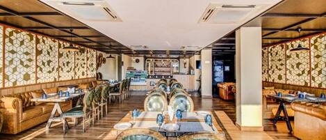 Un restaurante con suelo de madera, asientos tipo cabina acolchados de verde y una zona de bar central.