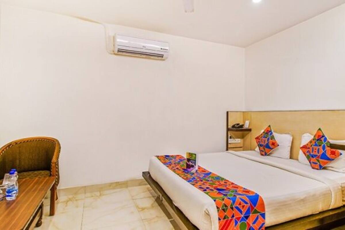 Una habitación de hotel con una cama, una silla, una mesa y un equipo de aire acondicionado.
