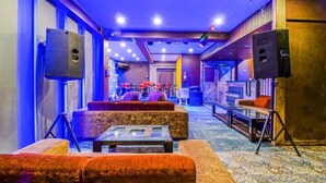 A lounge area with sofas, a coffee table, and a stage with musical equipment. - Fabhotel White Klove (New Delhi)