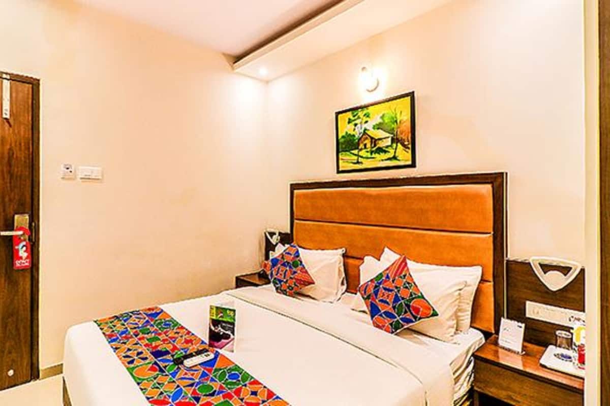 A hotel room with a bed, a nightstand, a wall-mounted painting, and a door.
