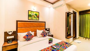 A hotel room with a bed, a nightstand, a painting on the wall, and a window with curtains. - Fabhotel Admiral (Mumbai)