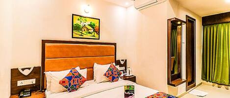 A hotel room with a bed, a nightstand, a painting on the wall, and a window with curtains.