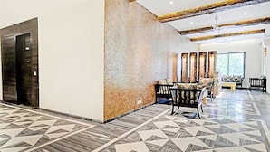 A spacious lobby with a geometric patterned floor, a seating area with a sofa and chairs, and a large wall with vertical panels. - Fabhotel Admiral (Mumbai)