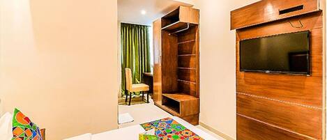 A hotel room with a bed, a TV, a wooden wardrobe, and a chair.