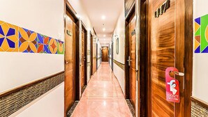 A hotel hallway with wooden doors, a tiled wall, and a marble floor. - Fabhotel Admiral (Mumbai)